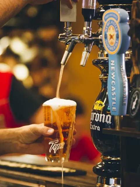 Cerveza de barril sirviéndose en un vaso de Tepa, junto a las llaves de Corona y Newcastle