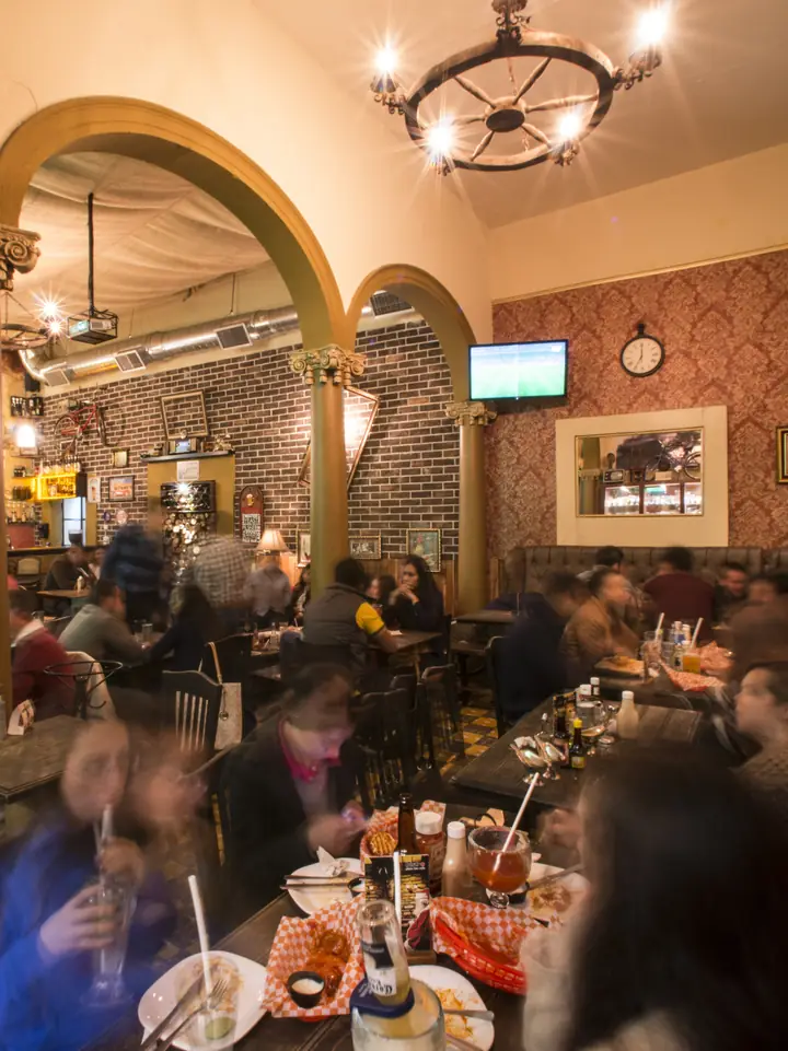El salón de Bistro 77 con arcos, lámparas y mesas llenas